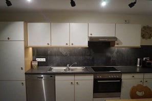 A kitchen with white cabinets, a stainless steel dishwasher, a built-in oven, and a microwave. - Holiday apartment Schwarzerd (Buchenberg)