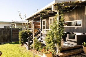 A covered outdoor area with a wooden staircase, outdoor furniture, and potted plants. - Chiara`s Art Cottage 1BR Coastal Garden Retreat (Sorrento)