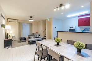Ein modernes Wohnzimmer mit einer Couch, einem Esstisch und einer Küchenzeile mit einer Mikrowelle.