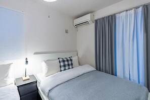 Ein Hotelzimmer mit Bett, Nachttischen, einer Klimaanlage und Vorhängen.