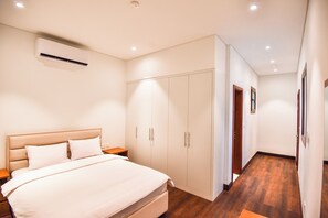 Ein Schlafzimmer mit Bett, Nachttischen, einem Kleiderschrank und einer Klimaanlage.