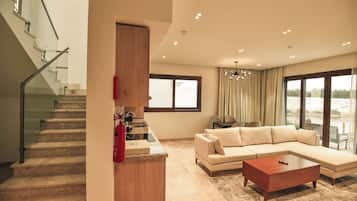 A modern living room with a staircase, a large sectional sofa, a coffee table, and a dining area.