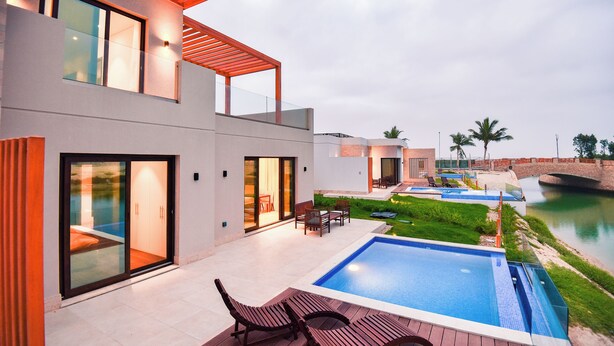 A modern house with a swimming pool, outdoor furniture, and a view of a river. - Private Pool Villa in Hawana Salalah — 5 min to the Beach (Taqah)
