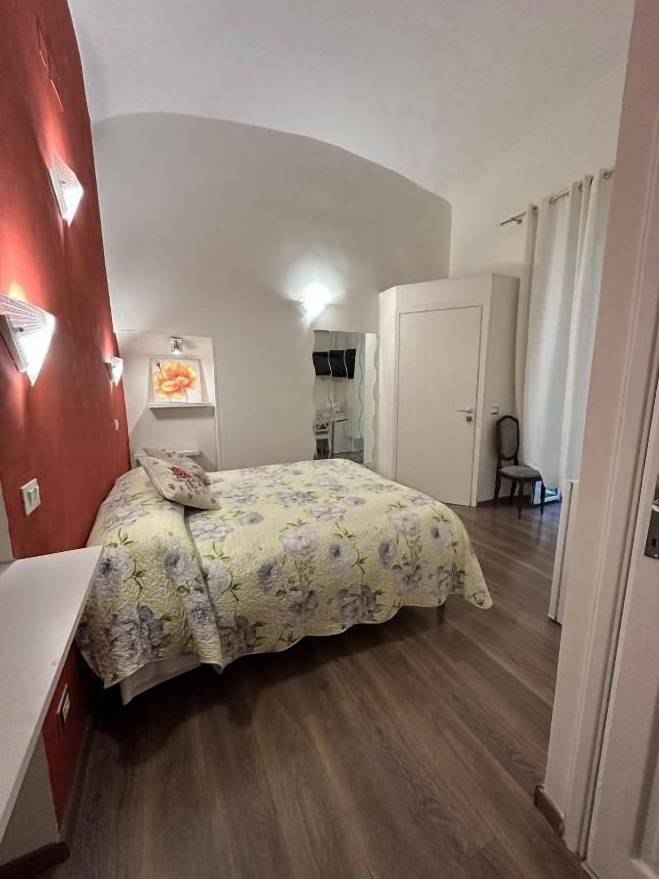 Un dormitorio con cama, escritorio y silla. Se ve una puerta y un espejo en la pared.