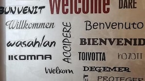 Una pared con un cartel que dice 'Welcome' rodeado de varias palabras en distintos idiomas.