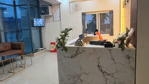 A reception area with a marble counter, a sofa, and a television. - Sri Raj Residency  (Kolar)