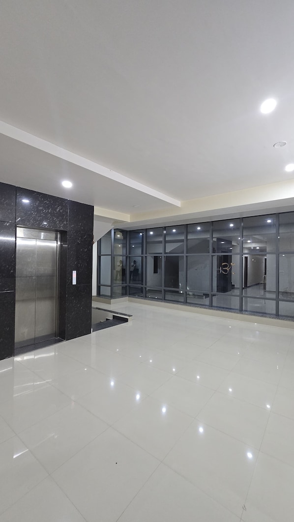A spacious lobby with a modern elevator and glass walls.