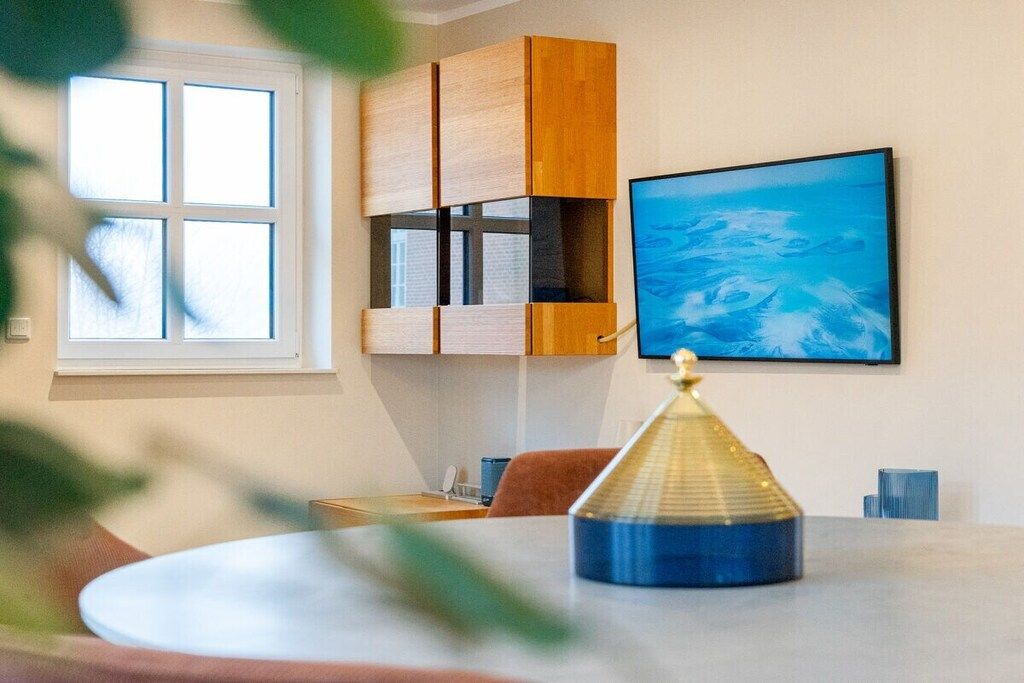 Une pièce avec une table ronde, une fenêtre, une étagère fixée au mur et un tableau.