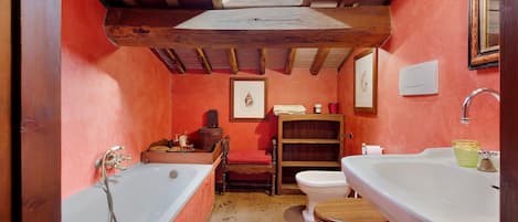 A compact bathroom with a skylight, a bathtub, a toilet, and a sink.