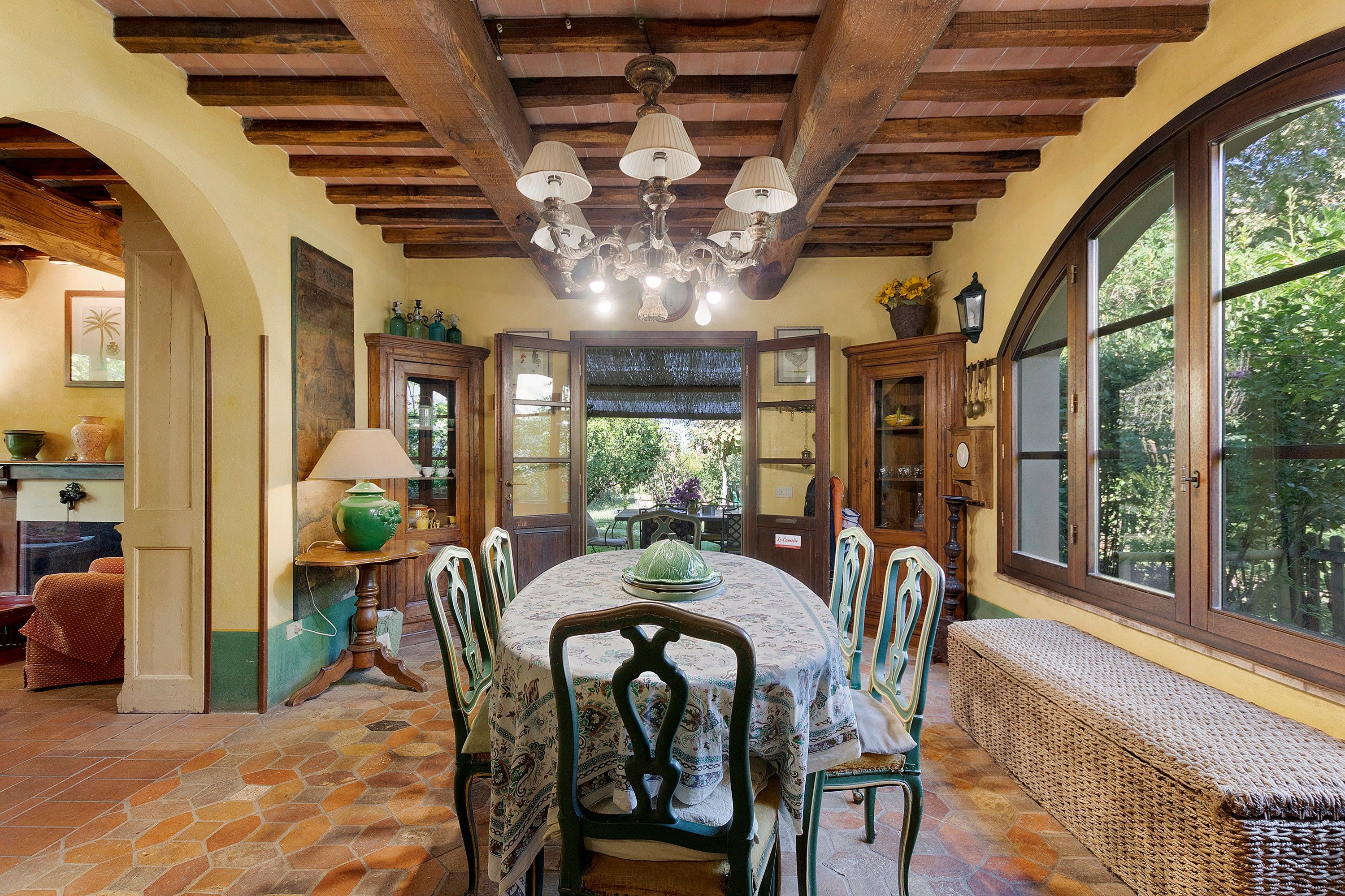 A dining area with a round table, chairs, and a chandelier.