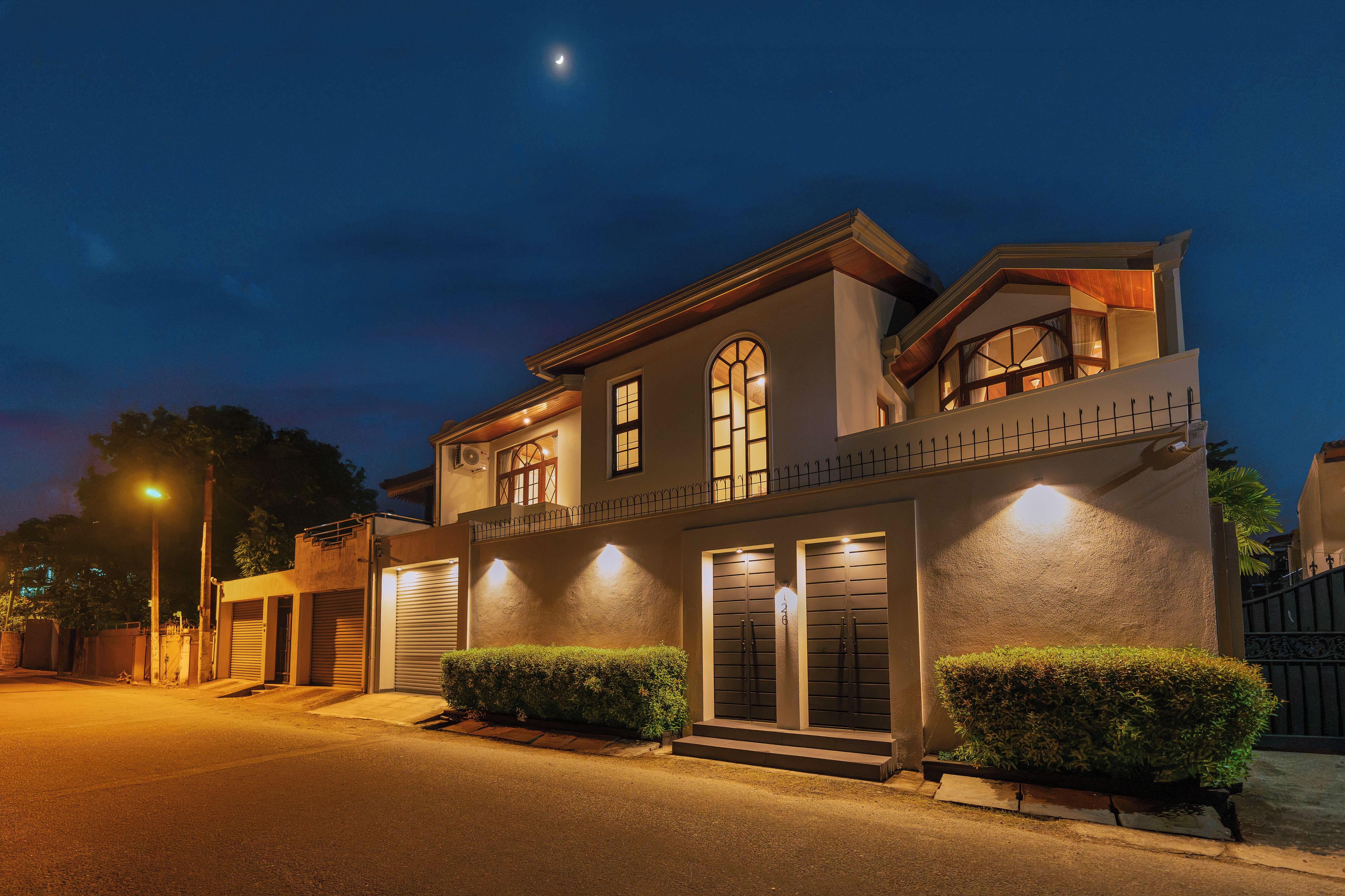 A two-story house with a balcony, large windows, and a well-lit entrance.