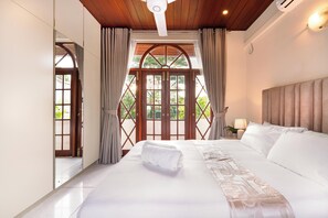 Een hotelkamer met een groot bed, een houten plafond en uitzicht door een raam met gordijnen.