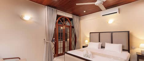 A hotel room with a bed, bedside lamps, a ceiling fan, and an air conditioning unit.