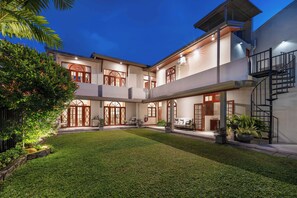 Un edificio de dos pisos con un patio cubierto y un césped bien cuidado.