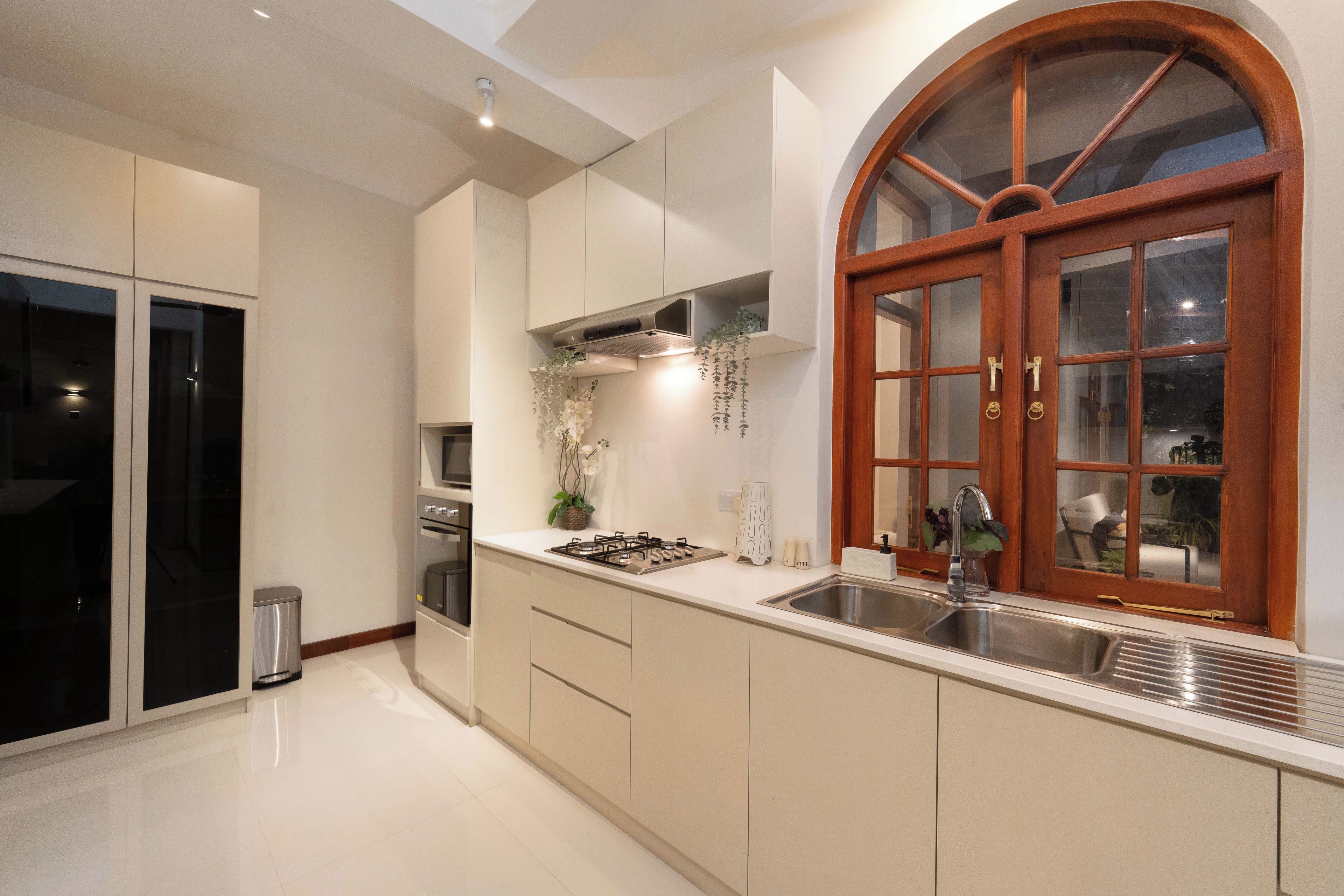 A modern kitchen with a large arched window, stainless steel appliances, and a clean, minimalist design.