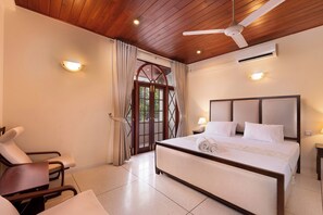 Ein Hotelzimmer mit Bett, Stuhl, Deckenventilator und Blick durch eine Tür.