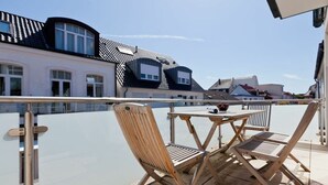 A balcony with a table and chairs, overlooking a residential area with houses. - Holiday apartment with 2 bedrooms (Norderney)