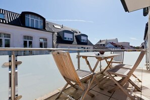 Ein Balkon mit Tisch und Stühlen, mit Blick auf eine Wohngegend mit Häusern.