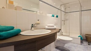 A bathroom with a sink, mirror, toilet, and shower. - Holiday apartment with 2 bedrooms (Norderney)