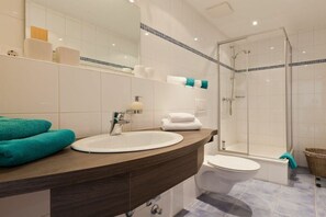 Ein Badezimmer mit Waschbecken, Spiegel, Toilette und Dusche.