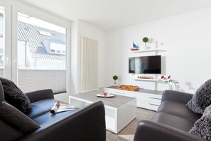 Ein modernes Wohnzimmer mit einem Flachbildfernseher, einem Couchtisch und zwei Sofas.