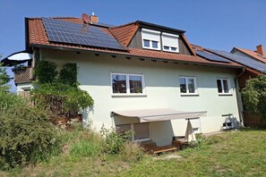 A two-story house with a sloped roof, solar panels, and a covered outdoor seating area. - Holiday apartment with 1 bedroom (Kemmern)