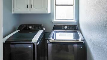 A laundry room with two front-loading washers and a window above.
