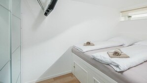 Et soveværelse med en seng, en vægmonteret klimaanlæg og en lille hylde med en plante.