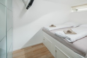 Ein Schlafzimmer mit einem Bett, einer Wand-Klimaanlage und einem kleinen Regal mit einer Pflanze.