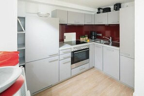 Eine kleine Küche mit weißen Schränken, einem Backofen, einer Spüle und einer Kaffeemaschine.