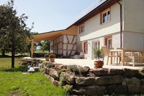 Uma casa tradicional em estilo de enxaimel com base de pedra, área de estar externa e plantas em vasos.