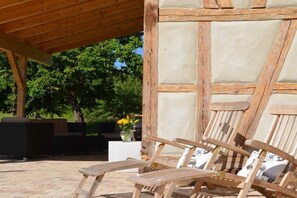 Un área de estar al aire libre con sillas de madera y un muro de piedra.