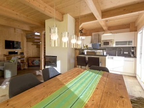 A wooden interior with a dining table, chairs, a kitchen area, and a television. - One-bedroom Cabin (Sankt Georgen am Kreischberg)