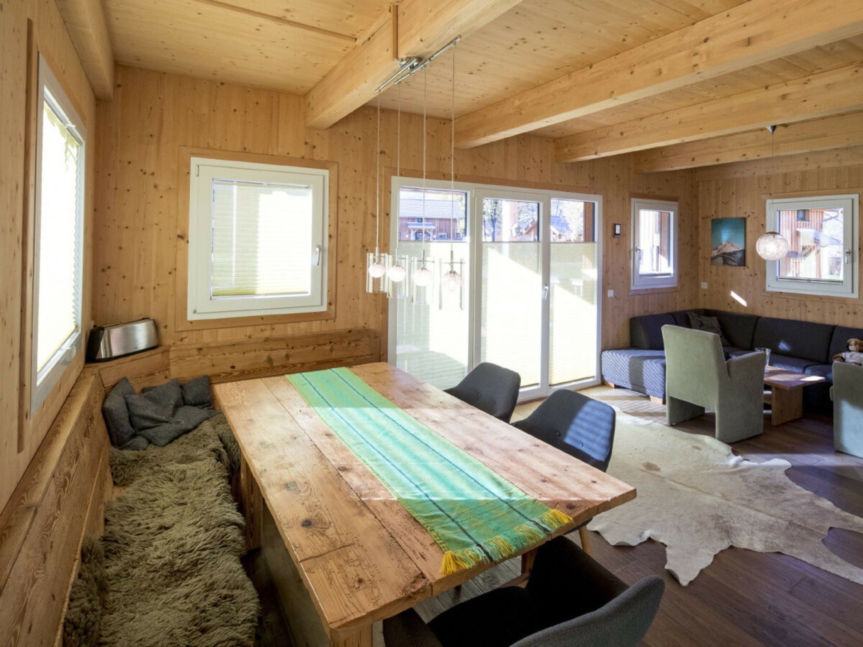Een houten interieur met een grote tafel, zitplaatsen en een bank.