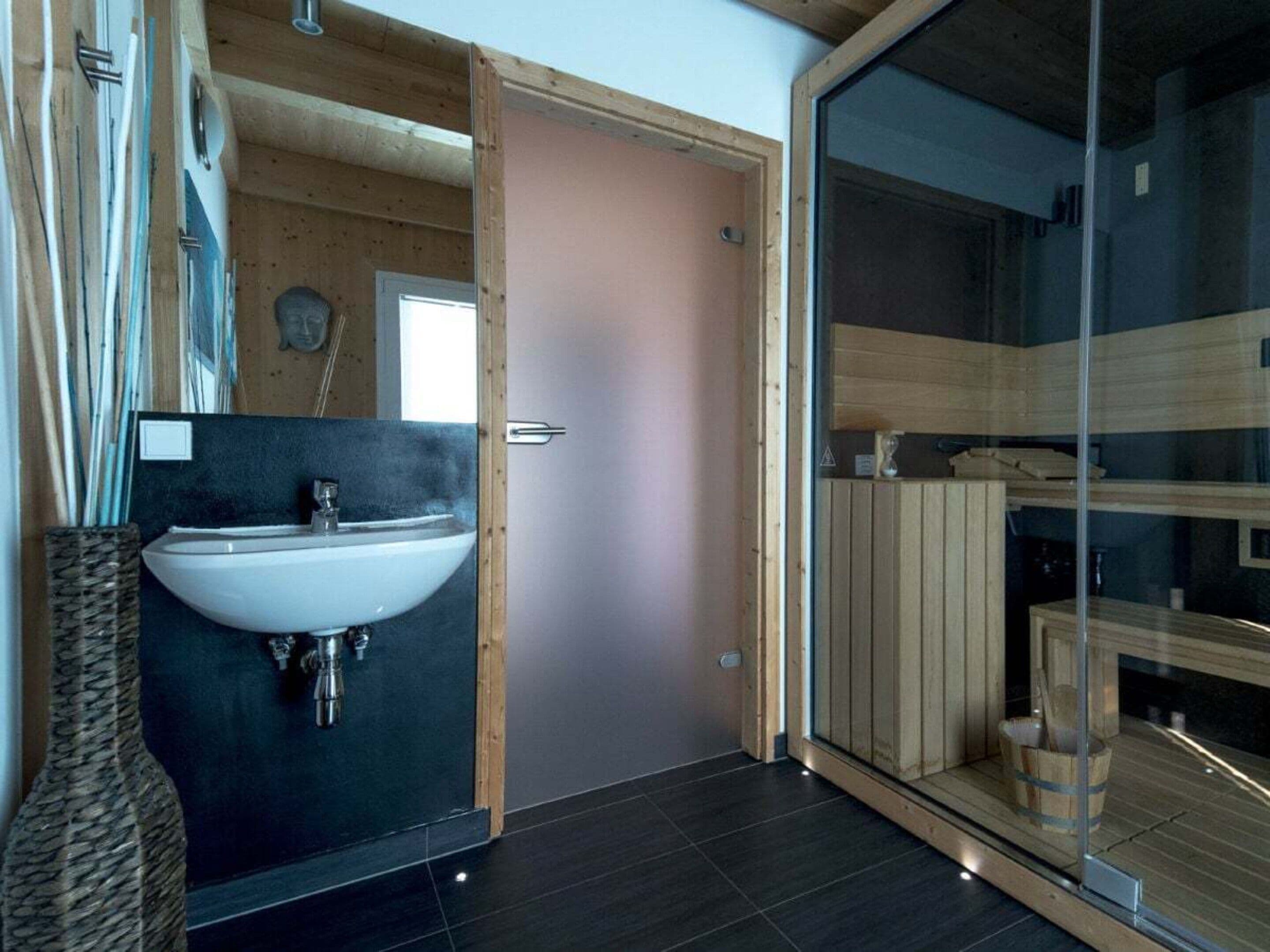 Une salle de bain moderne avec un grand lavabo, des murs en bois et une cabine de douche en verre.
