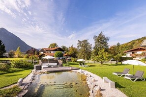 A mountain resort with a swimming pool, lounge chairs, and a view of the mountains. - Unterbrandnerlehen FeWo Königssee (Königssee)