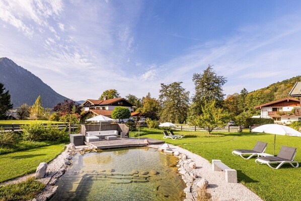 A mountain resort with a swimming pool, lounge chairs, and a view of the mountains.