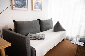 Ein modernes Zimmer mit einer Couch, einer Lampe, einem Tisch und zwei gerahmten Bildern an der Wand.