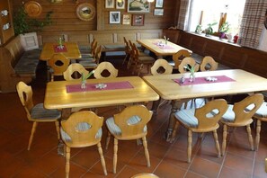 A restaurant interior with wooden tables and chairs, a bench seating area, and framed pictures on the walls. - Holiday apartment in Böbrach with Wi-Fi (Böbrach)