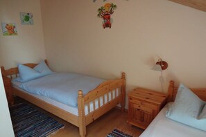 A single bed with a wooden frame and a matching nightstand, a small bedside table, and a wall-mounted lamp. - Holiday apartment in Böbrach with Wi-Fi (Böbrach)