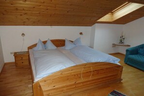 Een slaapkamer met een houten bed, een nachtkastje, een blauwe bank en een dakraam.