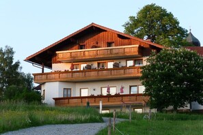 A multi-story building with balconies, a sloped roof, and a visible dome structure in the background. - Holiday apartment in Böbrach with Wi-Fi (Böbrach)
