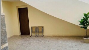 A room with a sloped ceiling, a door, two chairs, and a potted plant. - AWNY INN - Luxury Boutique Apartment & Café⁠ (El Qoseir⁠)
