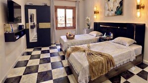 A hotel room with two beds, a television, a desk, and a window with curtains. - AWNY INN - Luxury Boutique Apartment & Café⁠ (El Qoseir⁠)