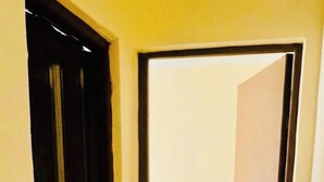 A hallway with a closed door on the left and an open door on the right leading to a tiled area. - AWNY INN - Luxury Boutique Apartment & Café⁠ (El Qoseir⁠)