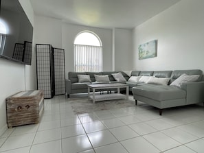 A modern living room with a sectional sofa, a coffee table, and a TV mounted on the wall. - Beautiful Vacation Home with Saltwater Pool, Lake View and SW Exposure (Naples)