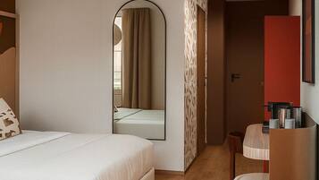 Una habitación de hotel moderna con una cama grande, un escritorio y un espejo.