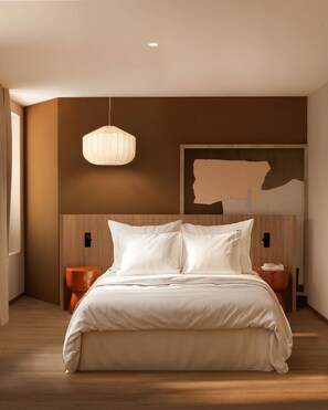 A modern bedroom with a large bed, wooden headboard, a hanging light fixture, and a painting on the wall. - OKKO Hotels Marseille Centre La Joliette (Marseille)