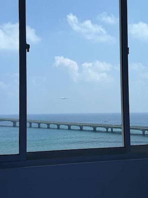 Vista de un puente sobre el agua, con un avión a lo lejos.