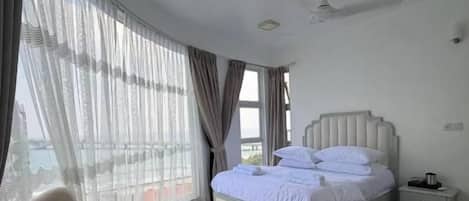 A bedroom with a bed, a chair, a bedside table, and a ceiling fan.